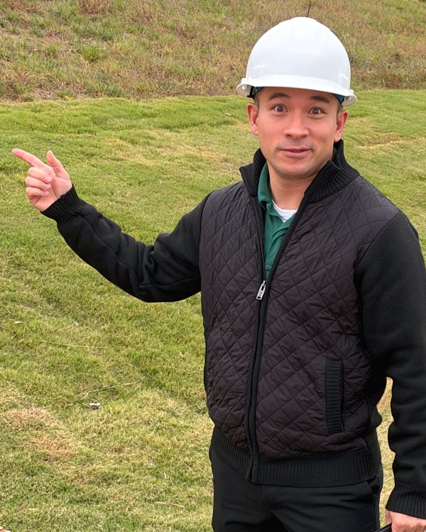 Charles Carper in a hard hat on a homesite, pointing
